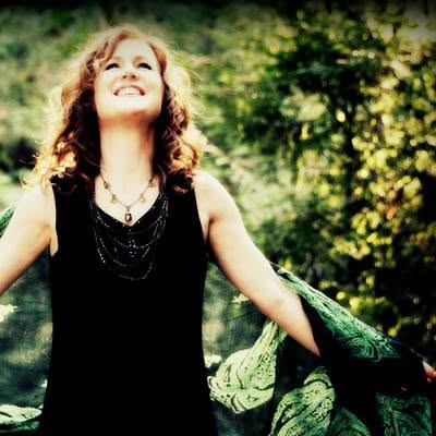 Lauri Jones portrait, laughing, in a green shawl against a forest backdrop